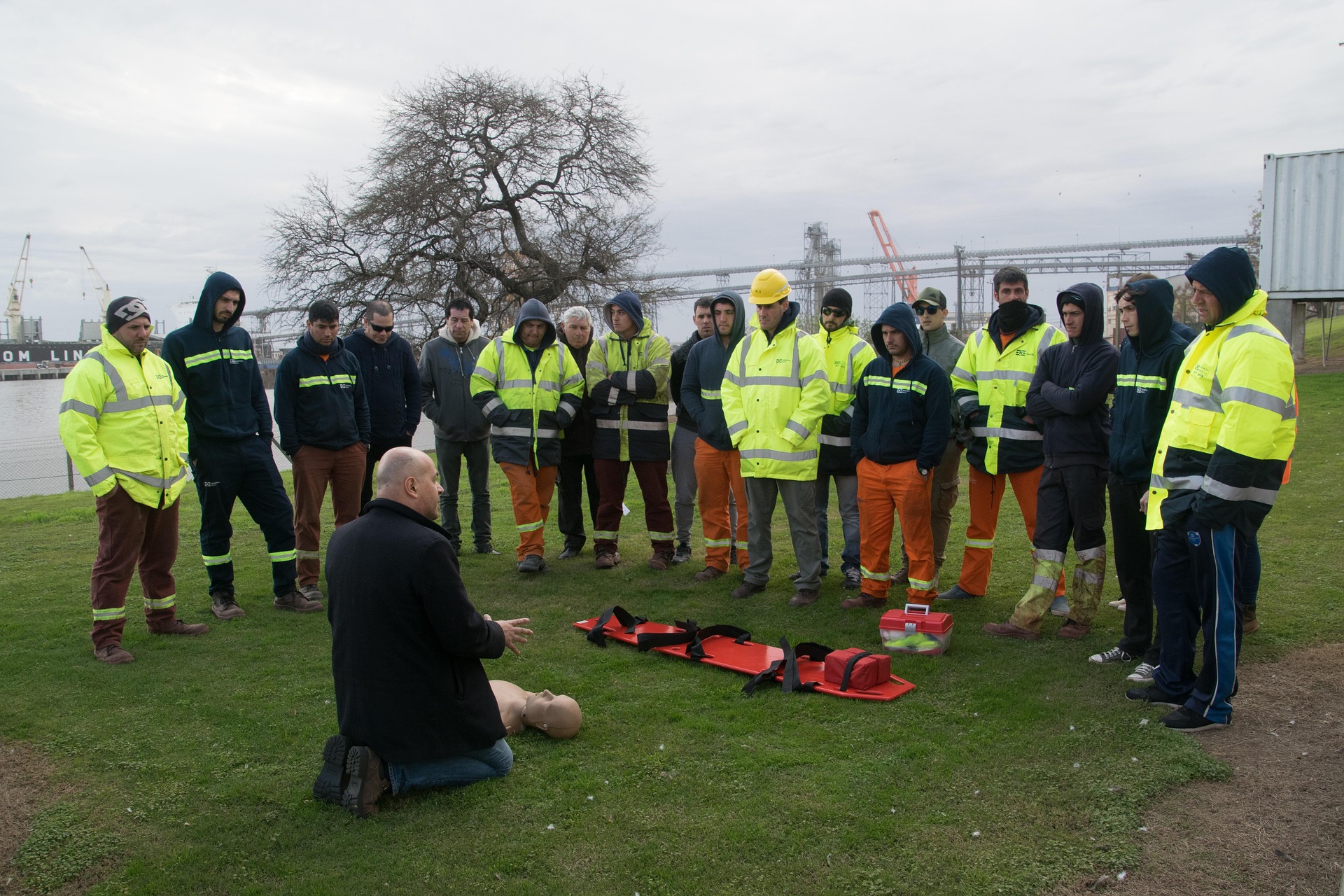 Certificación Internacional de RCP y DEA Un instructor de primeros auxilios realizando una capacitación a un grupo de personas con una camilla de rescate en el medio de ellos